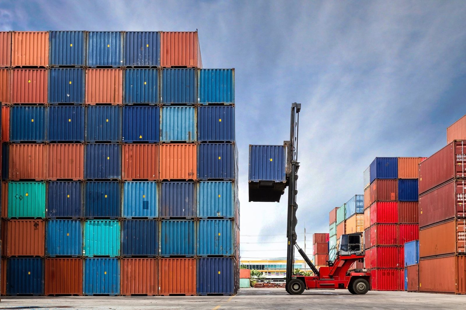 Stacked shipping containers being handled in a container yard